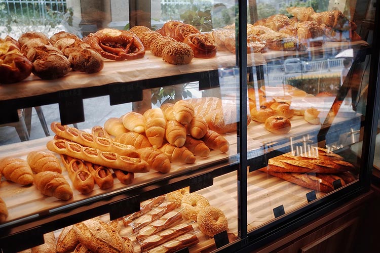 sweet pastries and bread products sitting on a benchtop in a window sill