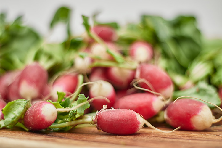 a pile of radishes sitting on a chopping board