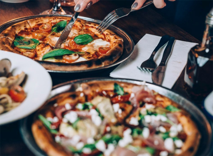 two-slices-of-pizza-from-compass-pizza a photo of two whole pizzas sitting side by side on a table