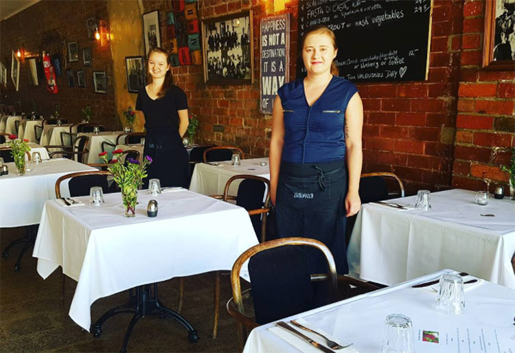 two-waitresses-at-stonemill-347-restaurant two waitresses standing inside the stonemill 347 restaurant in brunswick beside tables