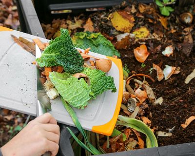 a woman pushing food scraps into a caddy