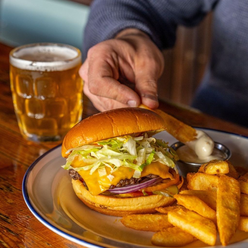miss moses a burger, fries and beer sitting on the table