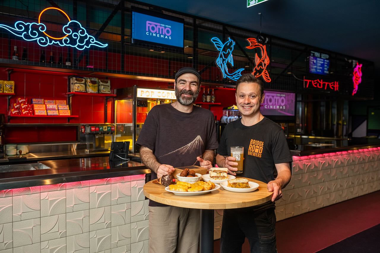 Fomo Cinemas two men standing inside at fomo cinemas enjoying food